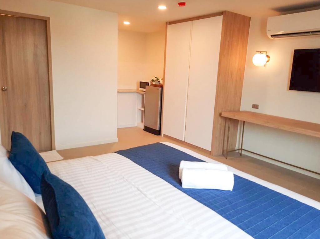 A reverse angle shows the bed, full-height wardrobe, entry door, kitchenette-like counter, and television wall.