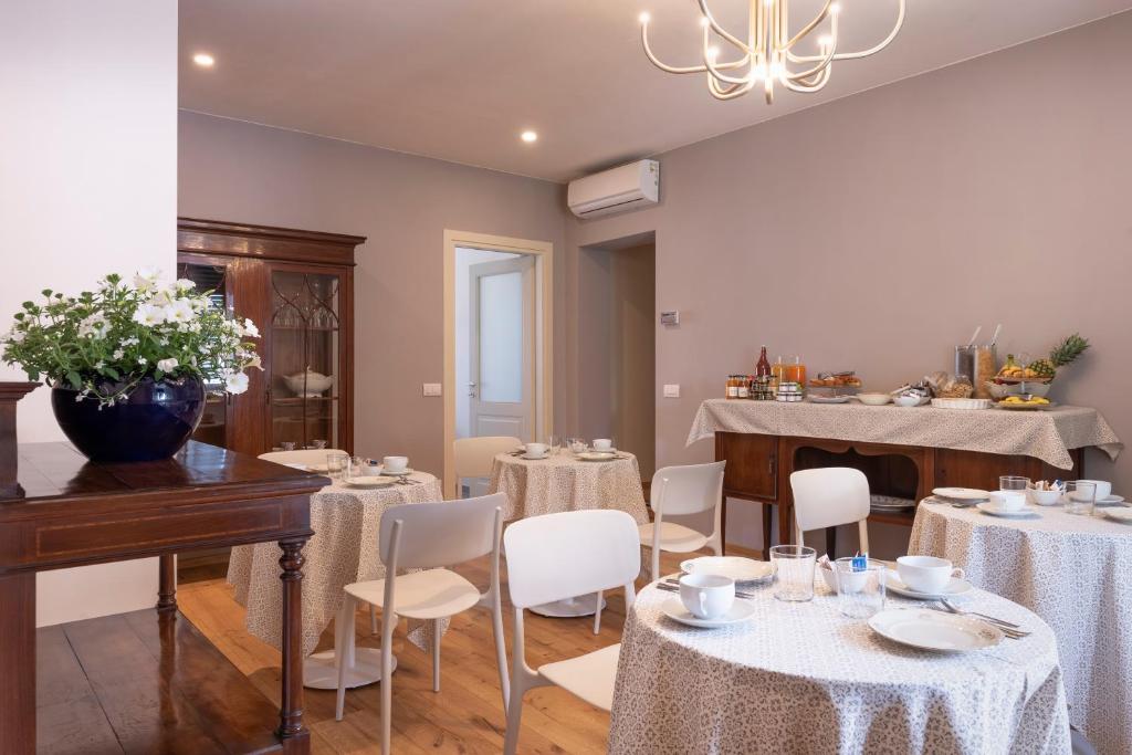 uma sala de jantar com mesas brancas e cadeiras brancas em IN LUCUS Guest House em Lucca