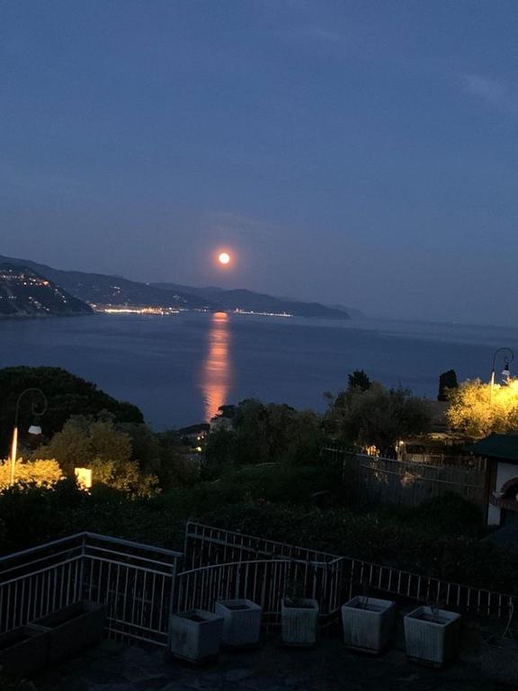 una luna llena elevándose sobre el agua por la noche en Lakshmi House, en Rapallo
