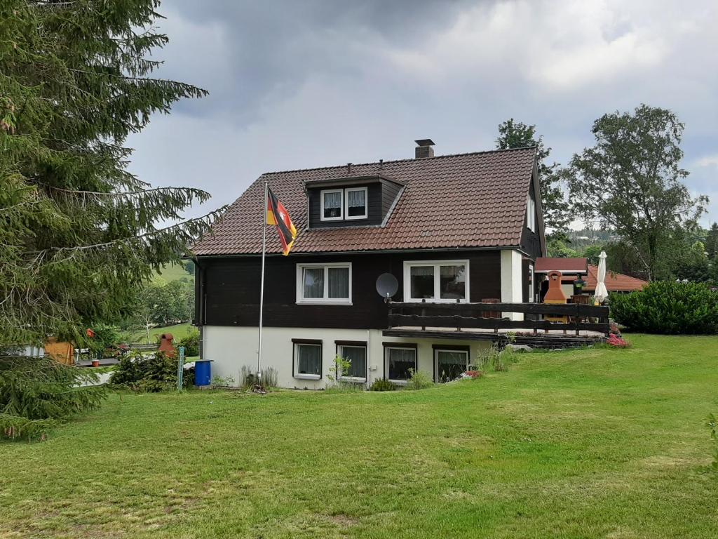 ein schwarzweißes Haus mit einer Flagge auf einem Hof in der Unterkunft Haus Rehblick FeWo-OG-3 in Sankt Andreasberg