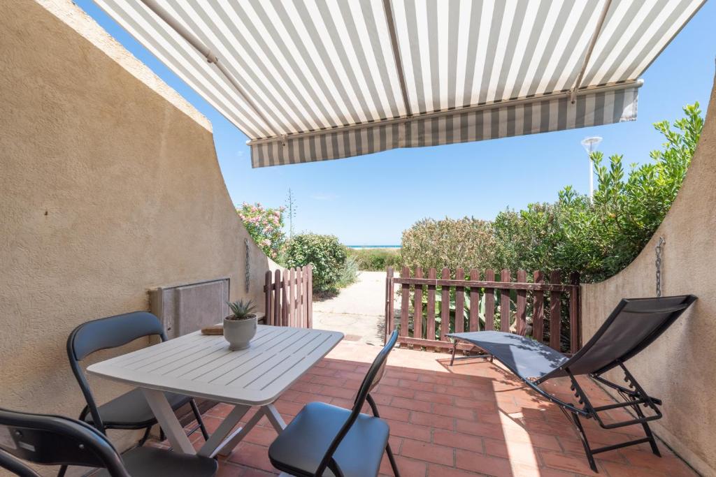 a patio with a table and chairs on a brick floor at La Dune in Leucate