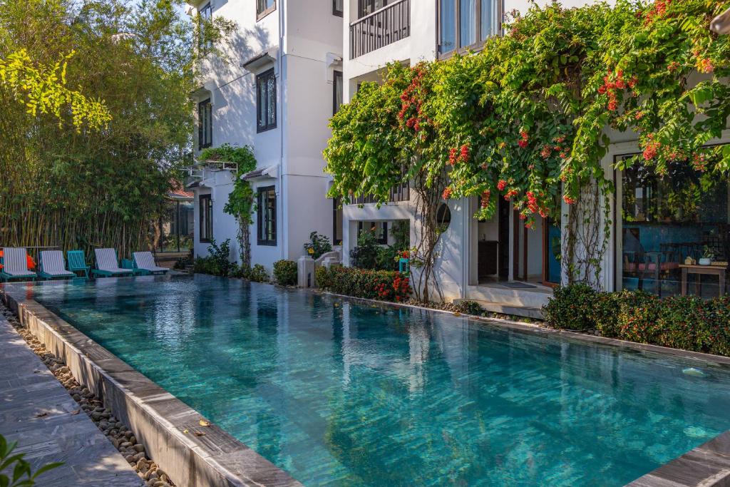a swimming pool with blue water in front of a building at Tra Que Mansion in Hoi An