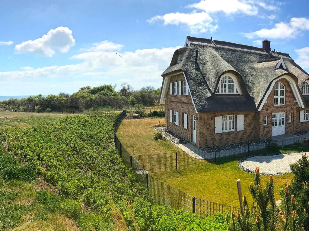 an old brick house with a roof on a field at Strandhaus 6 "Düne" in Lobbe mit Meerblick, Kamin, Sauna in Lobbe