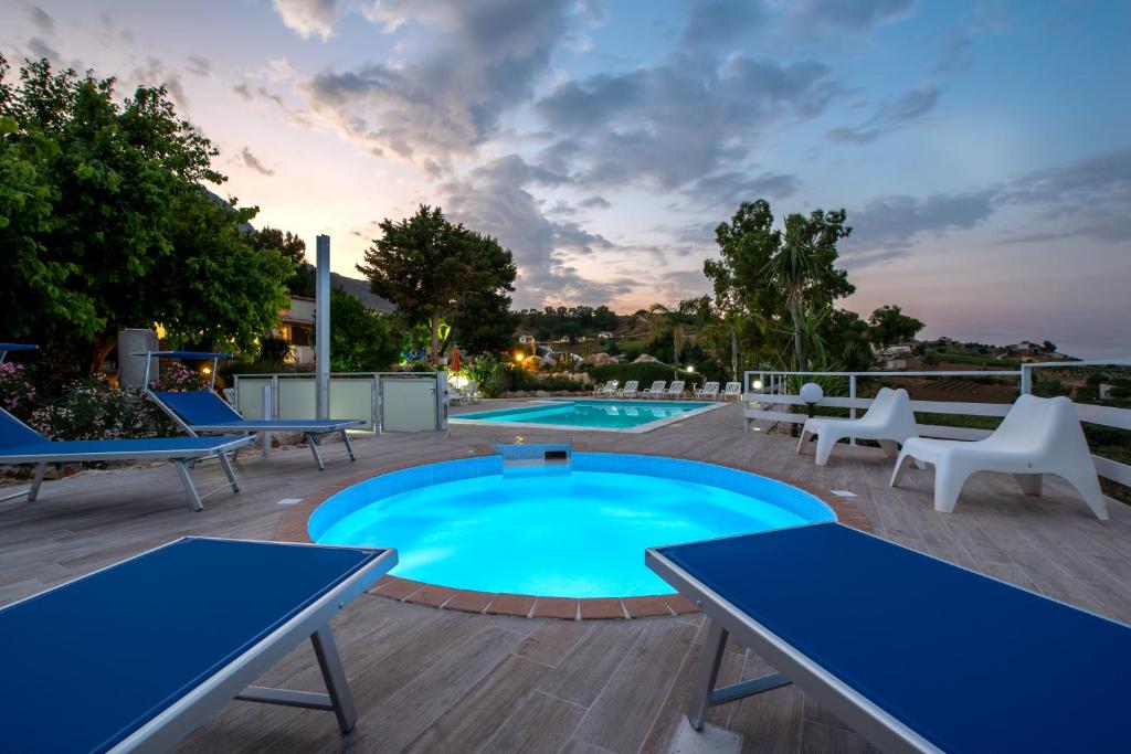 a swimming pool with blue tables and chairs on a deck at Green Holidays in Castellammare del Golfo