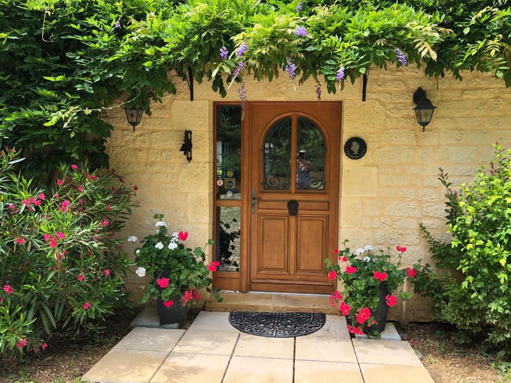 una casa con una porta in legno e alcuni fiori di Les Jonquilles a Domme