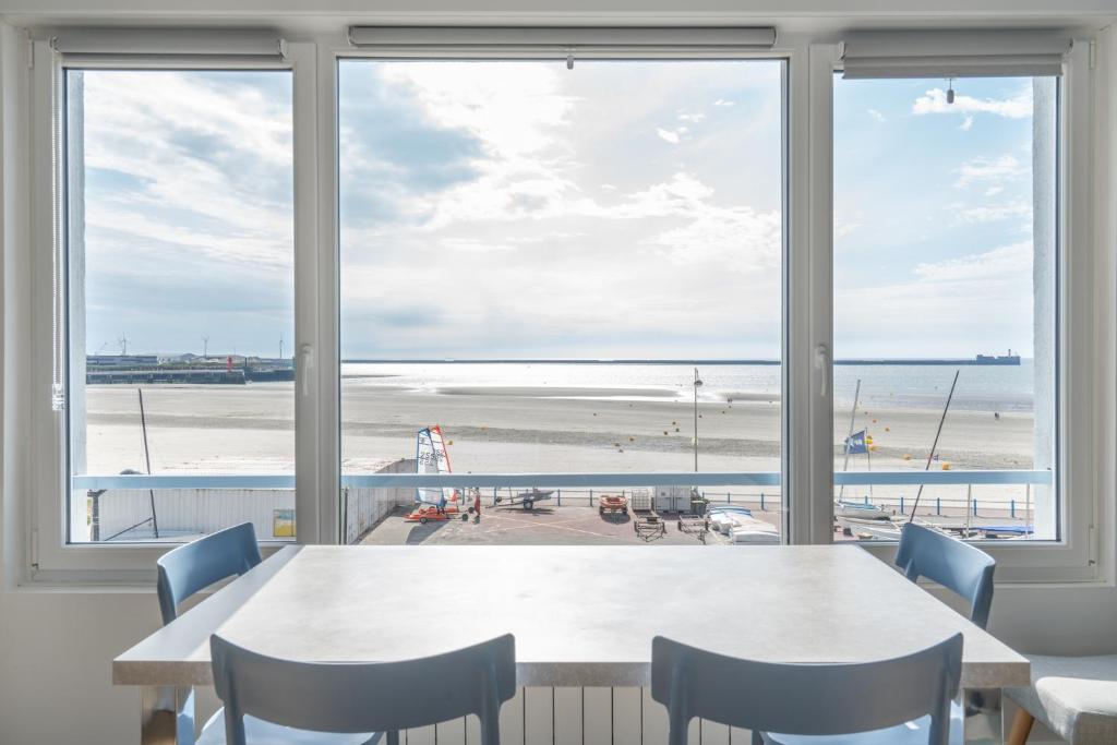 una sala da pranzo con tavolo e vista sulla spiaggia di "Les Mouettes" a Boulogne-sur-Mer