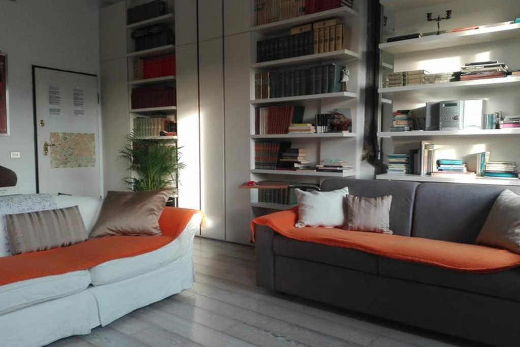 a living room with a couch and shelves with books at PINI in Florence