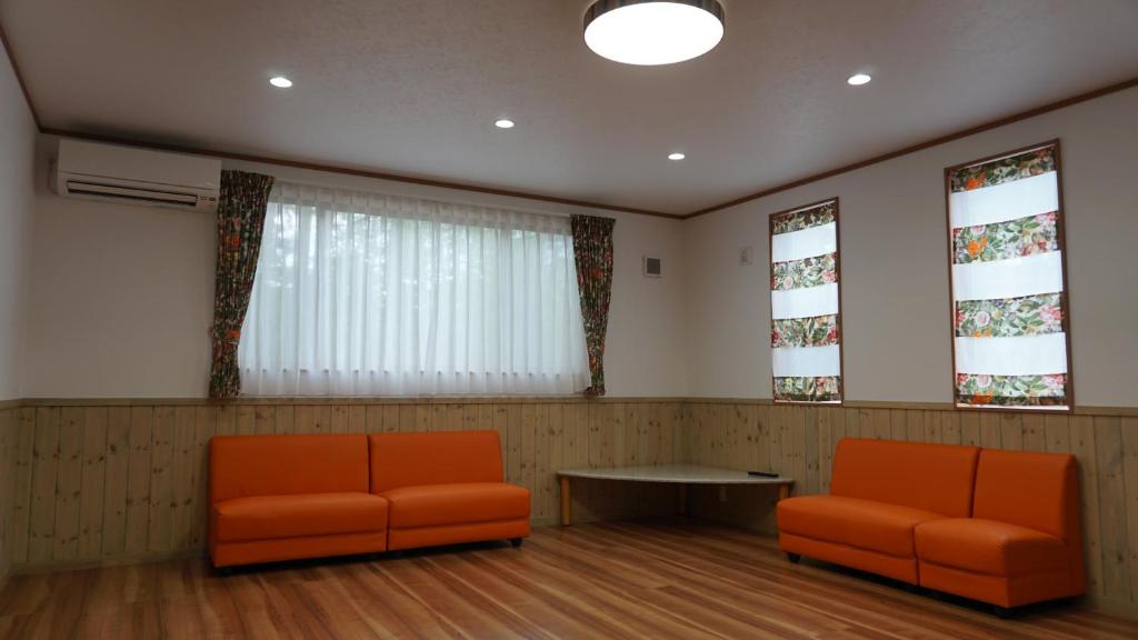 two orange chairs and a table in a waiting room at Forest minami kawaguchiko in Fujikawaguchiko