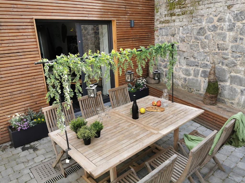 een houten tafel en stoelen op een patio bij L'Atelier in Houyet