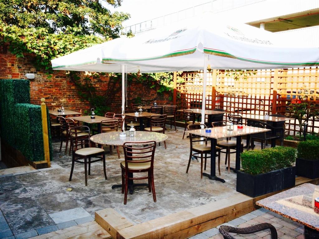 a patio with tables and chairs and an umbrella at Colchester Boutique Hotel in Colchester