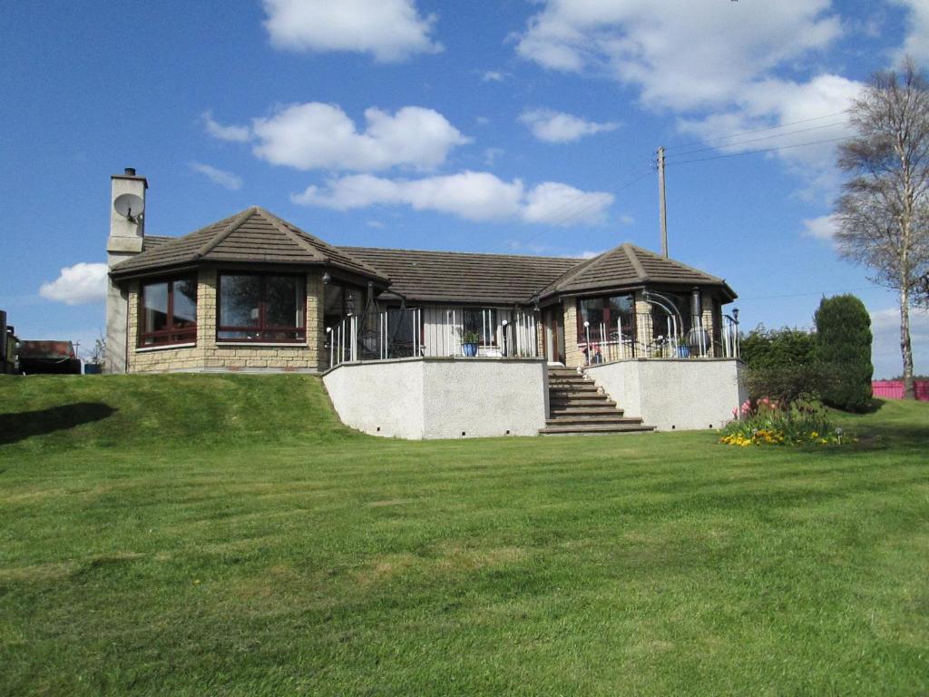 a house on a hill with a grass yard at Broomlea in Ardersier