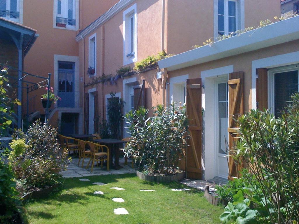 a small garden with a table and chairs next to a building at Hôtel de la Tour in Les Sables-dʼOlonne