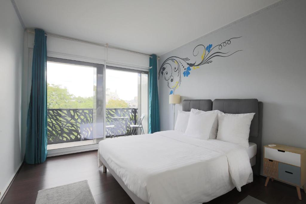 une chambre avec un lit blanc et une grande fenêtre dans l'établissement Appartement Ponthieu - HALA PARIS, à Paris