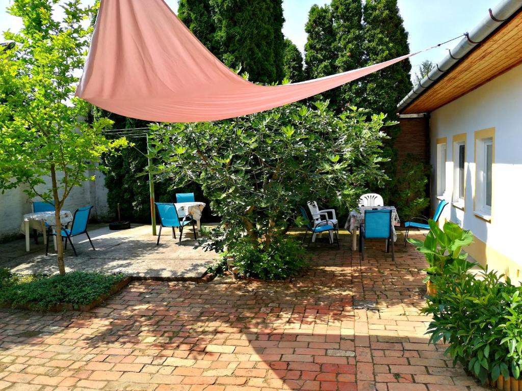 a patio with chairs and tables and a red umbrella at Brindza Vendégház in Szeged