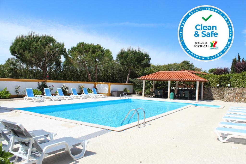 una piscina con sillas y un cenador con el logotipo de la caja fuerte limpia en Casa de Campo Sao Rafael - Turismo Rural en Óbidos