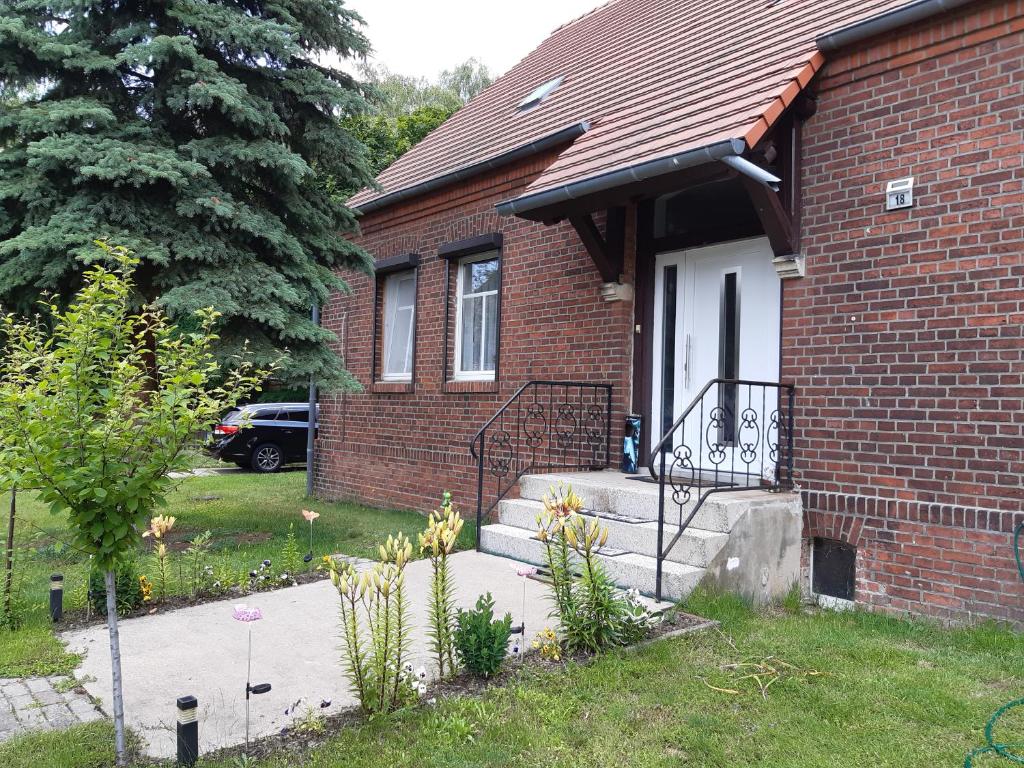 Cette maison en briques dispose d'une terrasse couverte et d'une porte blanche. dans l'établissement Ferienwohnung Runge II, à Schönhauser Damm