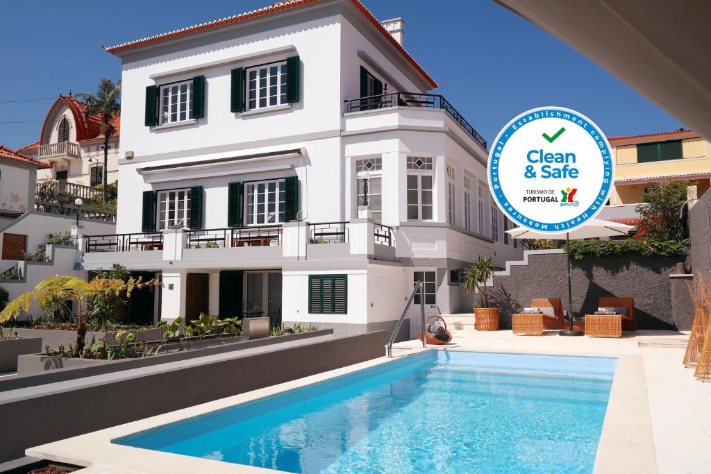 a villa with a swimming pool in front of a building at Quinta B. in Funchal