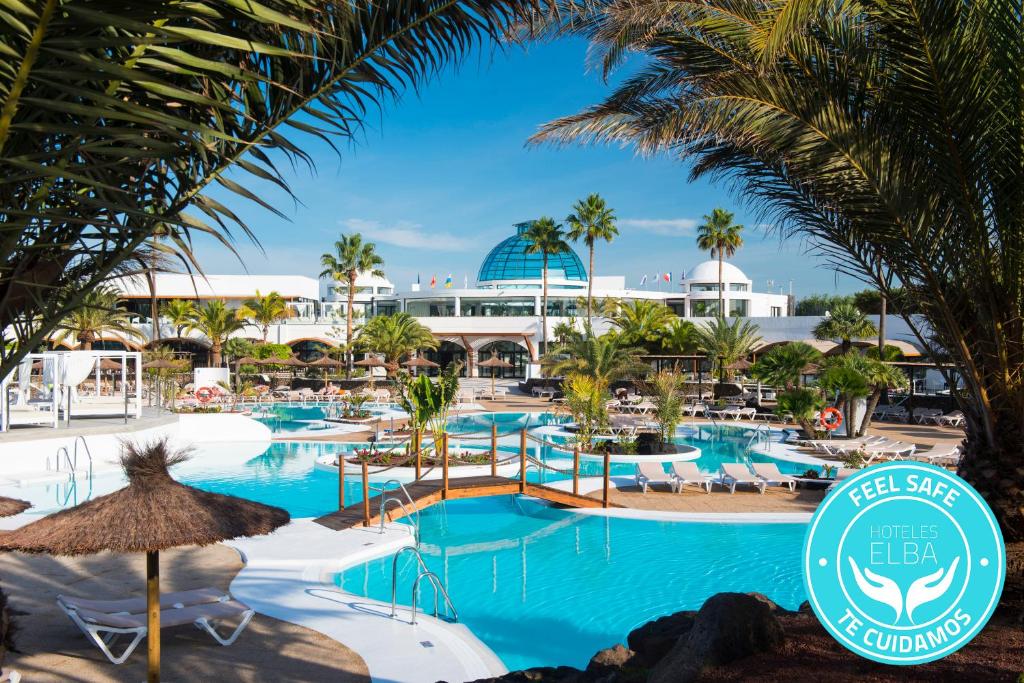 
a beach with palm trees and palm trees at Elba Lanzarote Royal Village Resort in Playa Blanca
