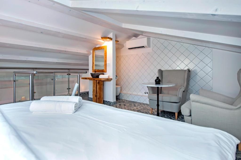 a bedroom with a large white bed and a chair at Casa Colloredo Free Parking in Rovinj
