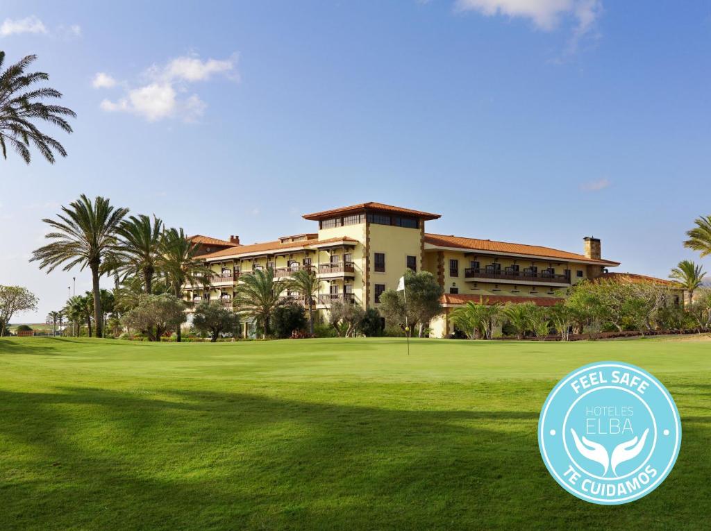 a large green building with a blue sky at Elba Palace Golf & Vital Hotel - Adults Only in Caleta De Fuste