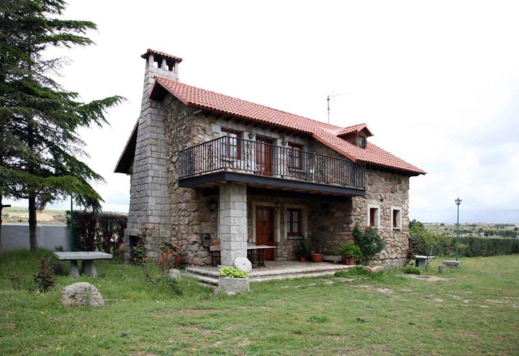 uma pequena casa de pedra com um alpendre e uma varanda em CASA TEO em Ávila