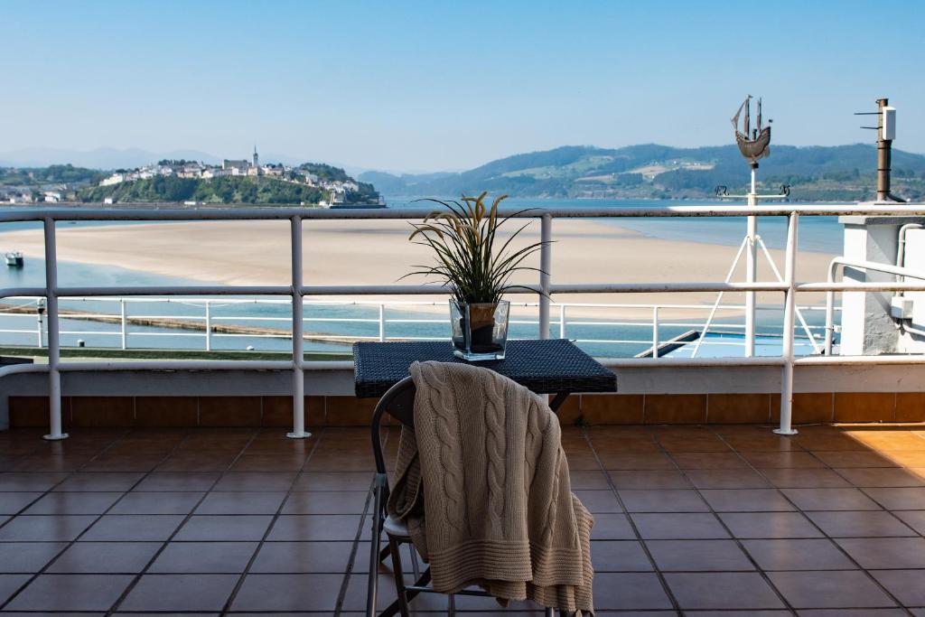 einen Tisch und einen Stuhl auf einem Balkon mit Blick auf den Strand in der Unterkunft HOLIDAY HOMES Figueras AT in Castropol