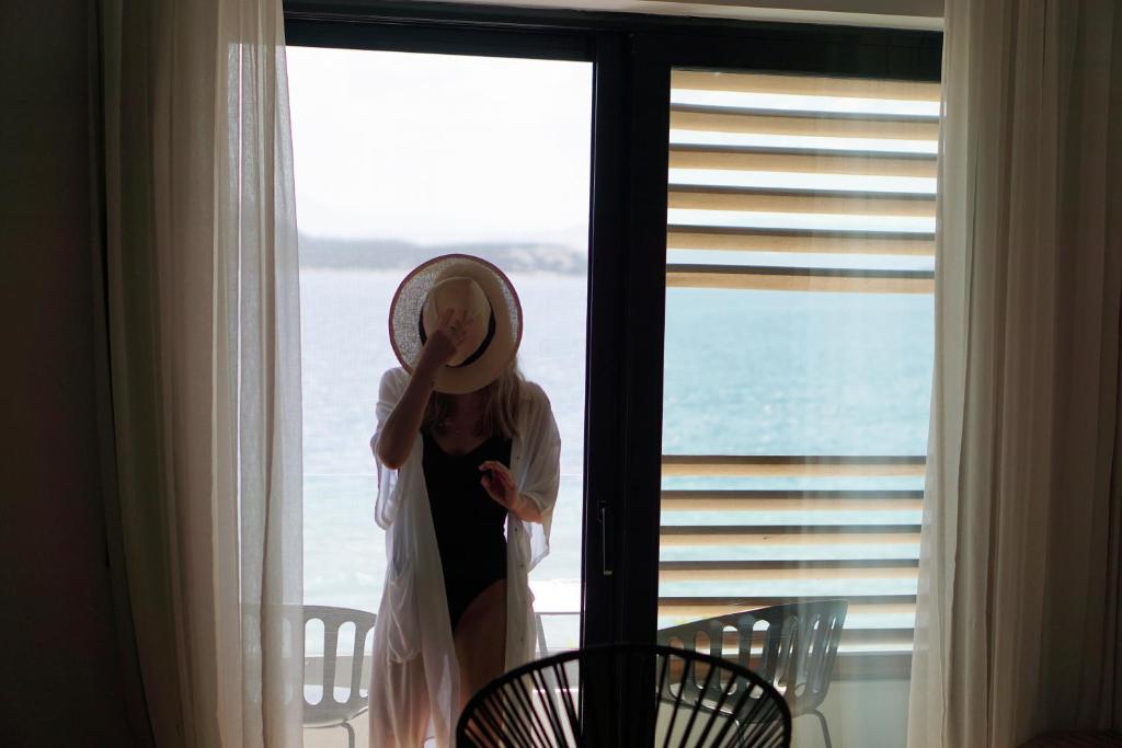 a girl standing in a window with a mirror on her face at Sunday Boutique Hotel in Nea Stira