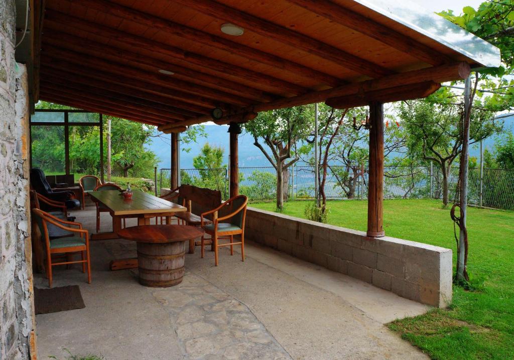 eine Terrasse mit einem Tisch und Stühlen unter einem Holzdach in der Unterkunft Old House Kontic in Nikšić