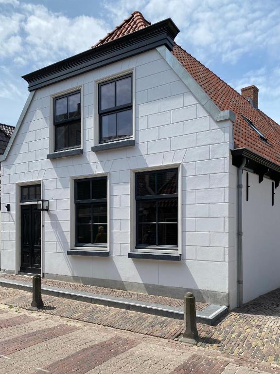 a white house with black windows on a street at Het Vergulde Visje in Den Burg