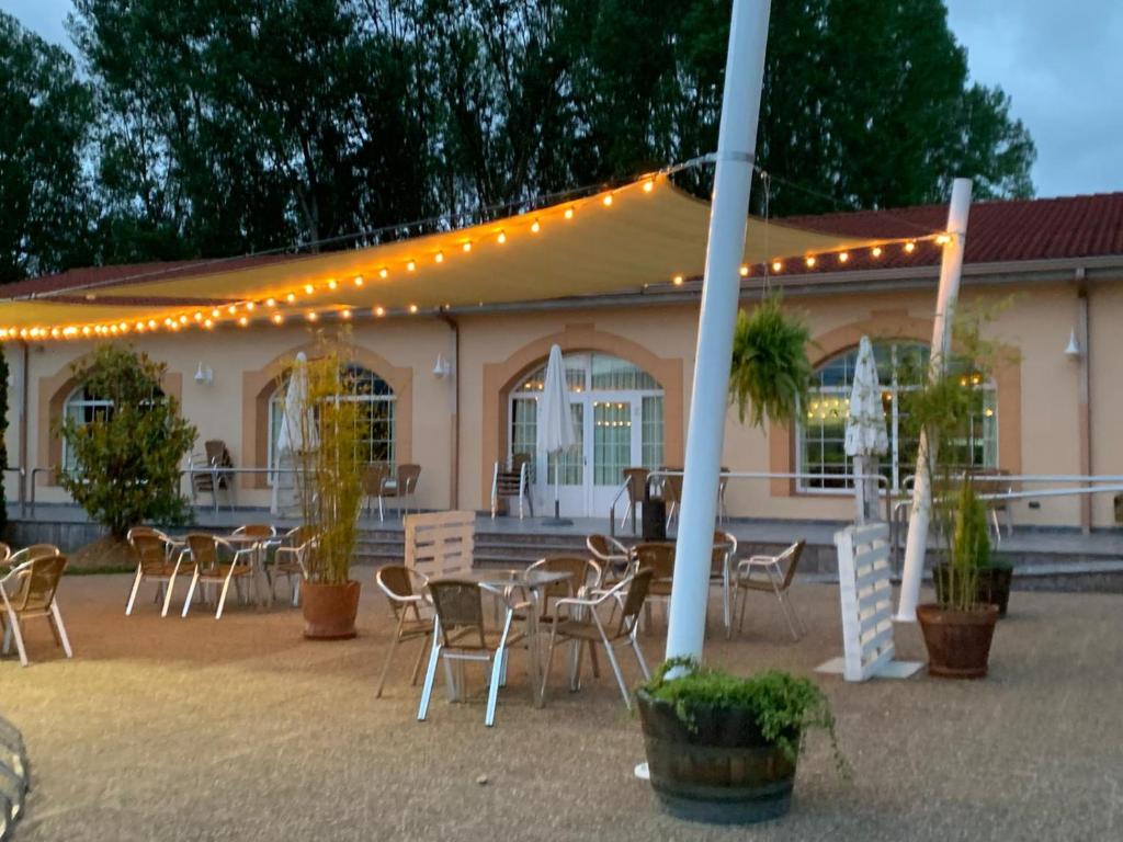 a patio with tables and chairs and a building with lights at Hotel Restaurante La Alhama in Medina de Pomar