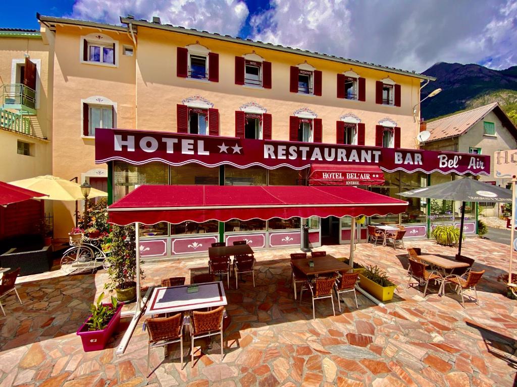 un hotel con mesas y sillas frente a un edificio en Hôtel Bel'Air en Jausiers