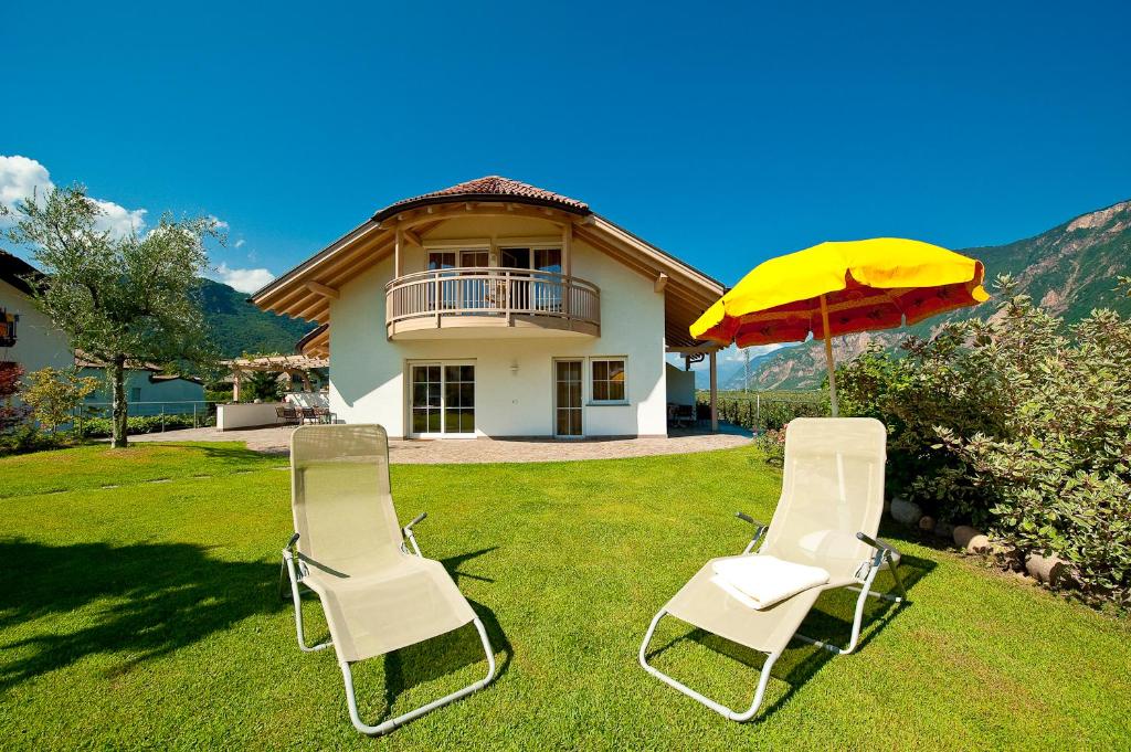 two chairs and an umbrella in the yard of a house at Villa Trogerhof in Ora/Auer