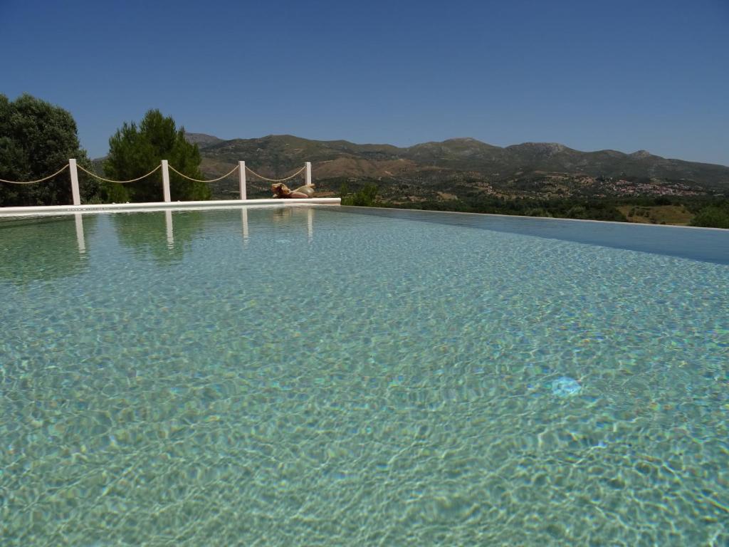 a large pool of clear blue water with mountains in the background at MELILOFOS STUDIO 1 BDR w Pool in Evia island in Avlonárion