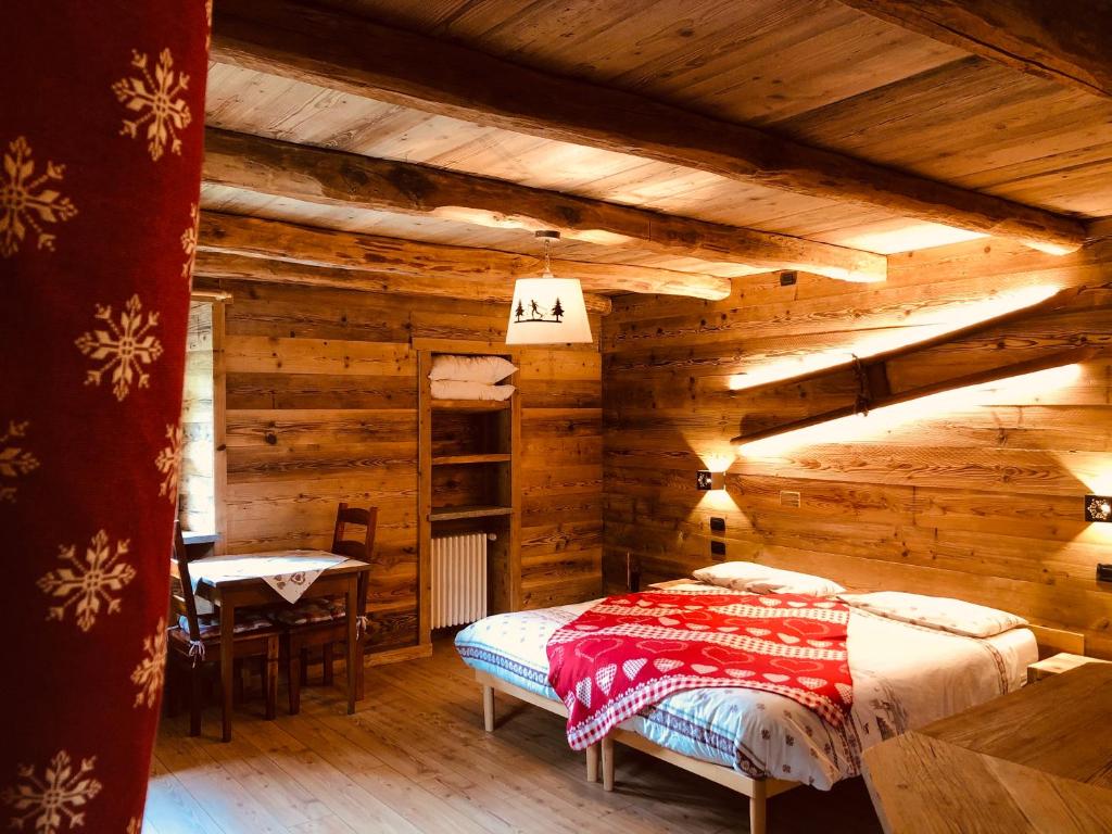 een slaapkamer met een bed in een blokhut bij Ospitalità rurale familiare Land Wasser in Varallo