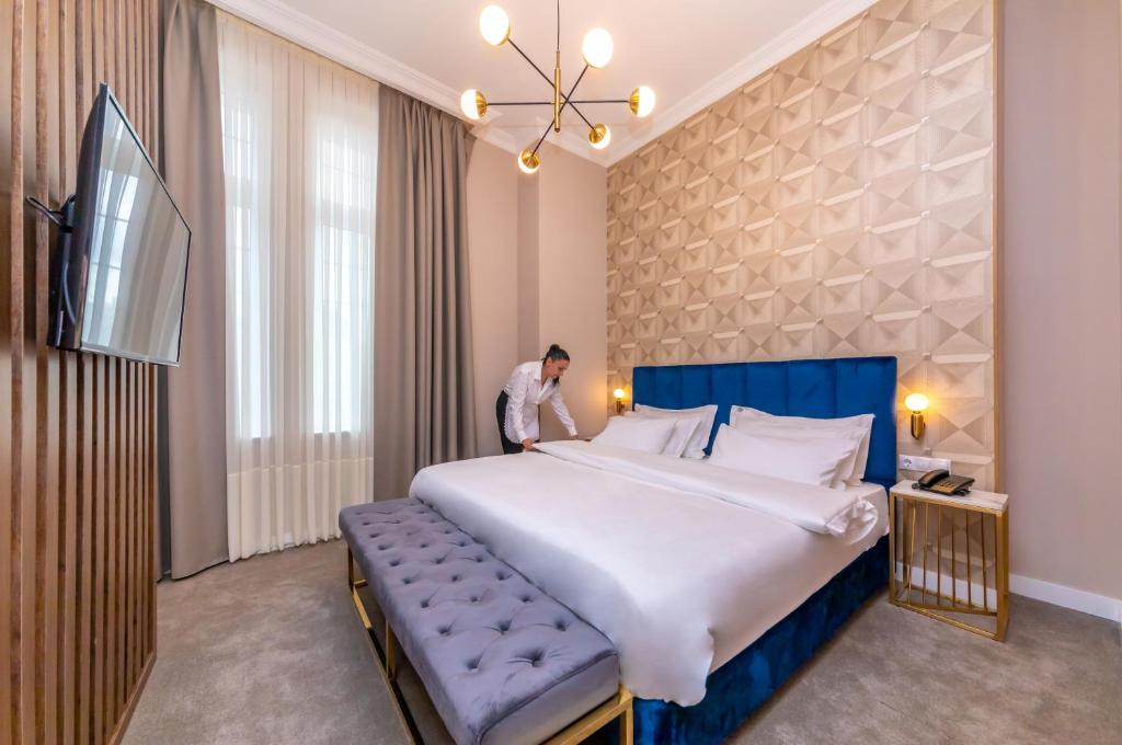 a man standing next to a large bed in a room at Newport Hotel Kutaisi in Kutaisi