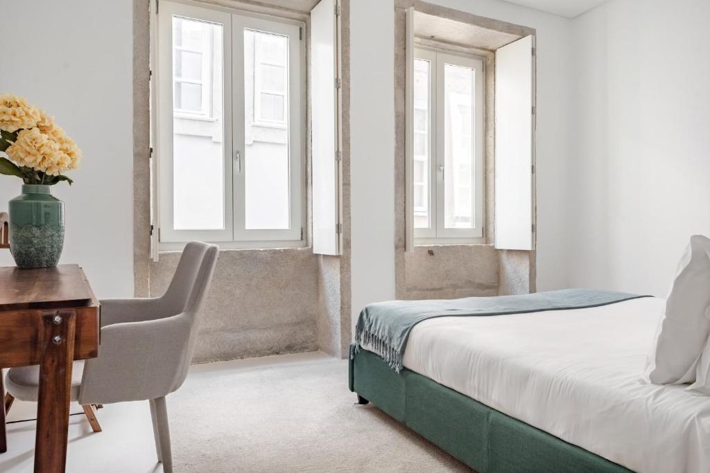 Schlafzimmer mit einem Bett, einem Schreibtisch und Fenstern in der Unterkunft Decompress at a Tranquil, Minimal Urban Oasis with an Edge in Porto