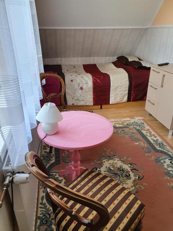 a pink table and a chair in a room with a bed at Domek nad jeziorem Rumian in Rybno