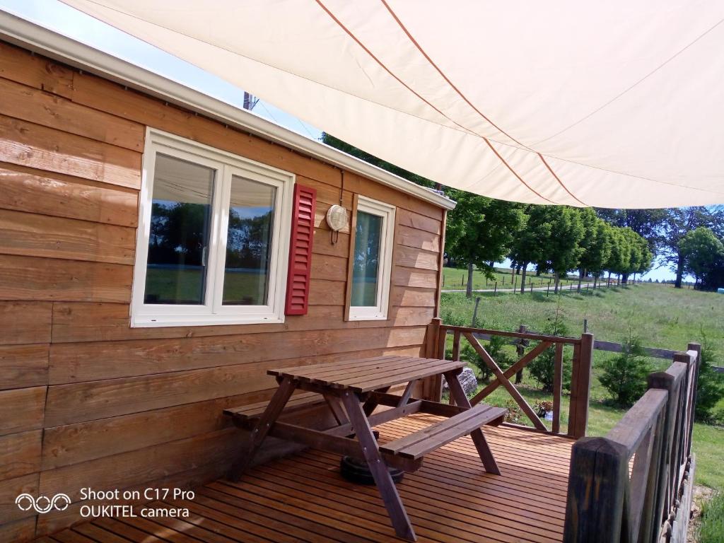 a wooden deck with a picnic table and a window at Les chalets de Bes Le Montagnol in Lacombe