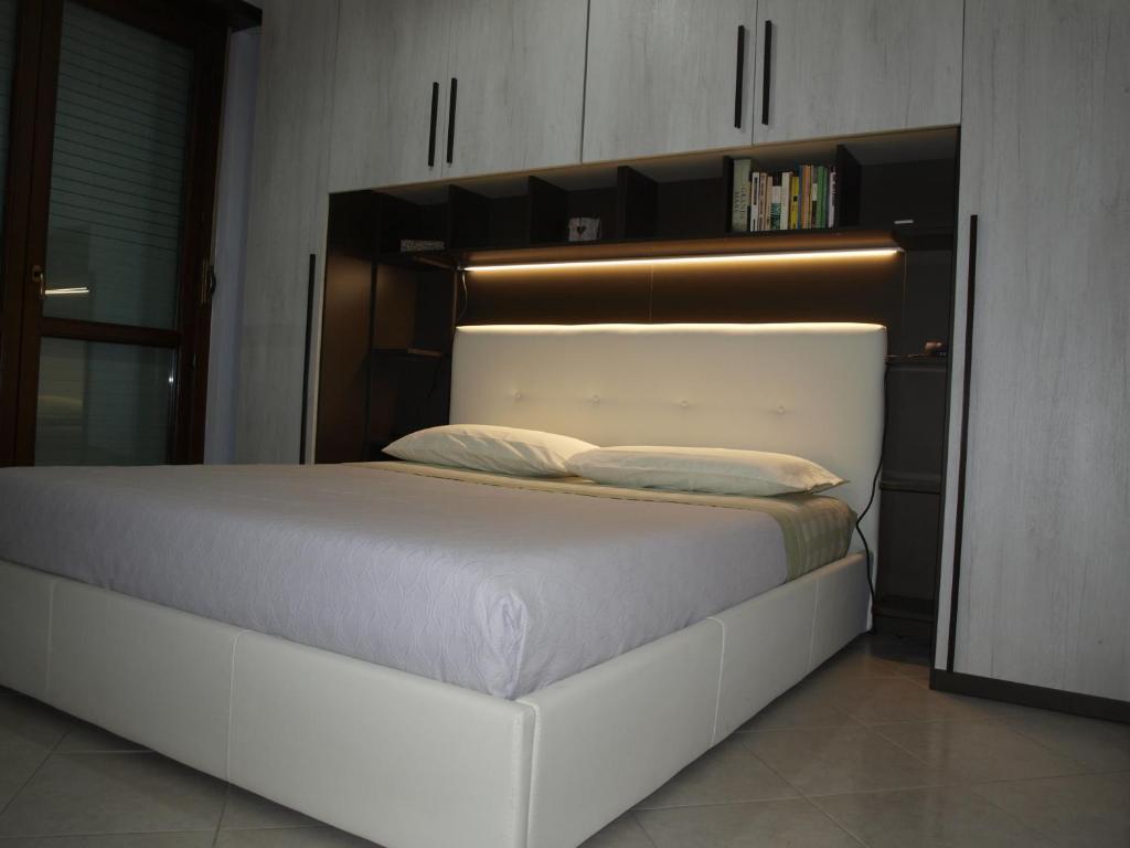 1 cama blanca grande con cabecero de madera en una habitación en Graziosarisa Roma, en Lunghezza