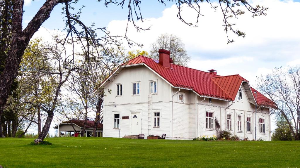 a white house with a red roof on a green field at Kartanomajoitus Sofia & Angelique in Pieksamaki