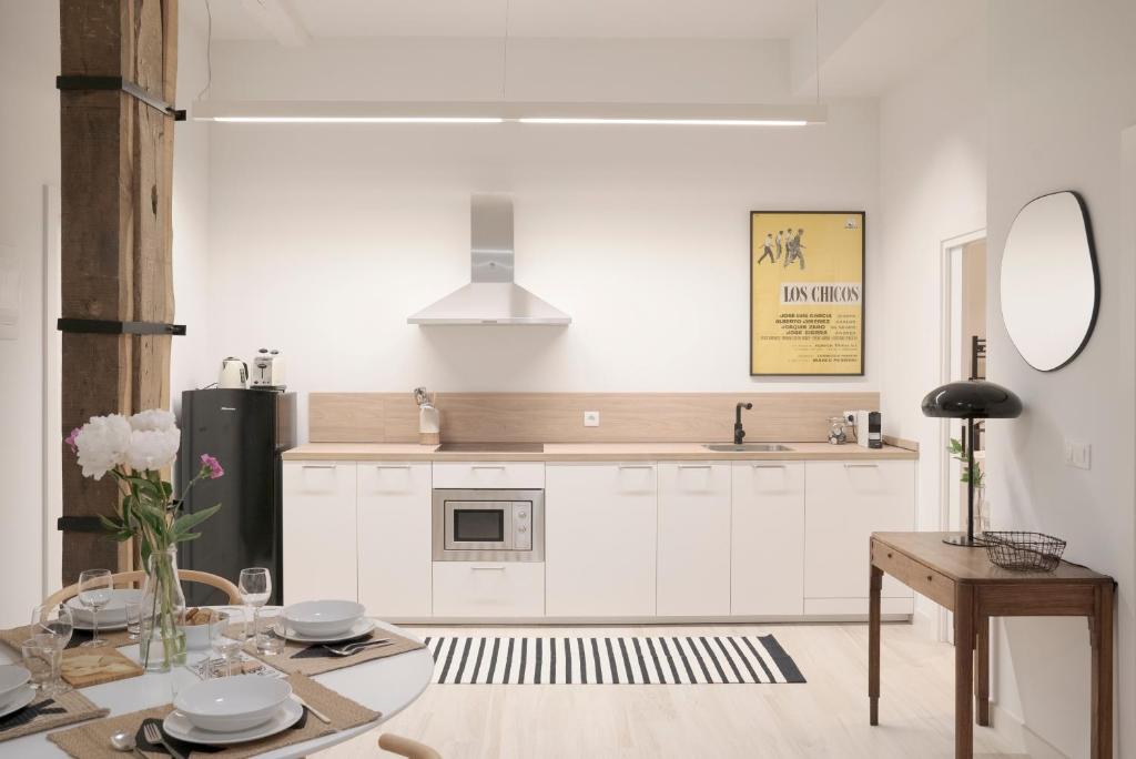 a kitchen with white cabinets and a table at NUEVO Katu Kale Apartamentuak CENTRO HISTORICO in Getaria