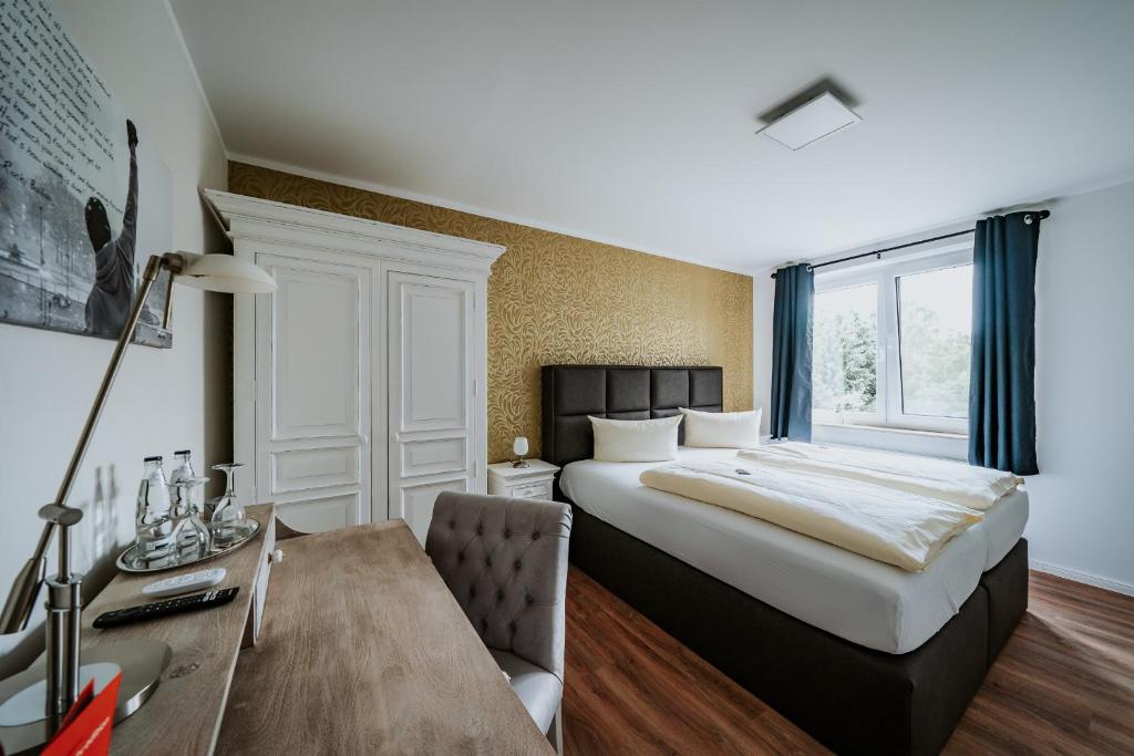 希登豪森的住宿－RobrookS Hotel Garni，酒店客房设有一张大床和一张书桌。