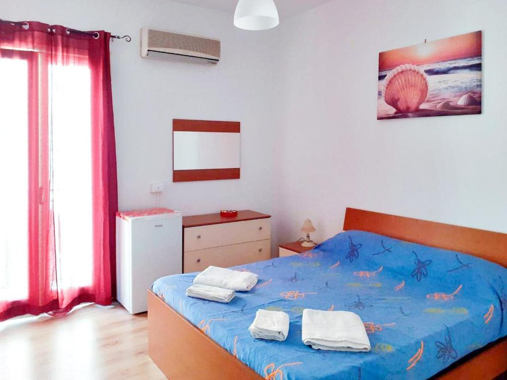 a bedroom with a blue bed with towels on it at Flamingo Room in Castellammare del Golfo