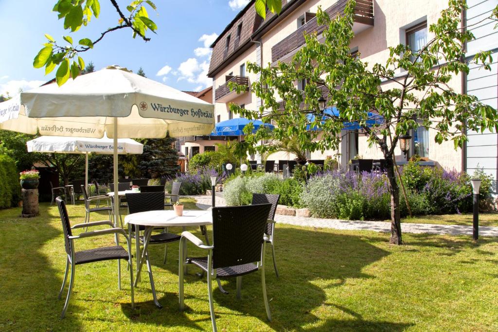 a table with chairs and an umbrella in a yard at Hotel Jägerhof in Staatsbad Brückenau