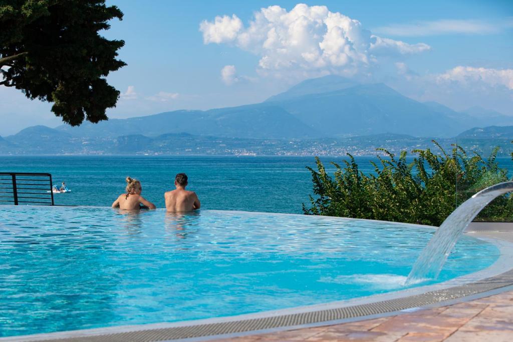 een groep mensen in een zwembad met uitzicht op het water bij Camping Bergamini in Peschiera del Garda