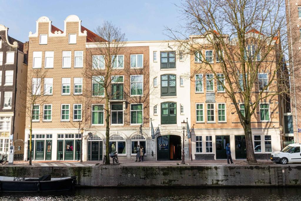 a building on the side of a river with a boat at Hotel Mai Amsterdam in Amsterdam