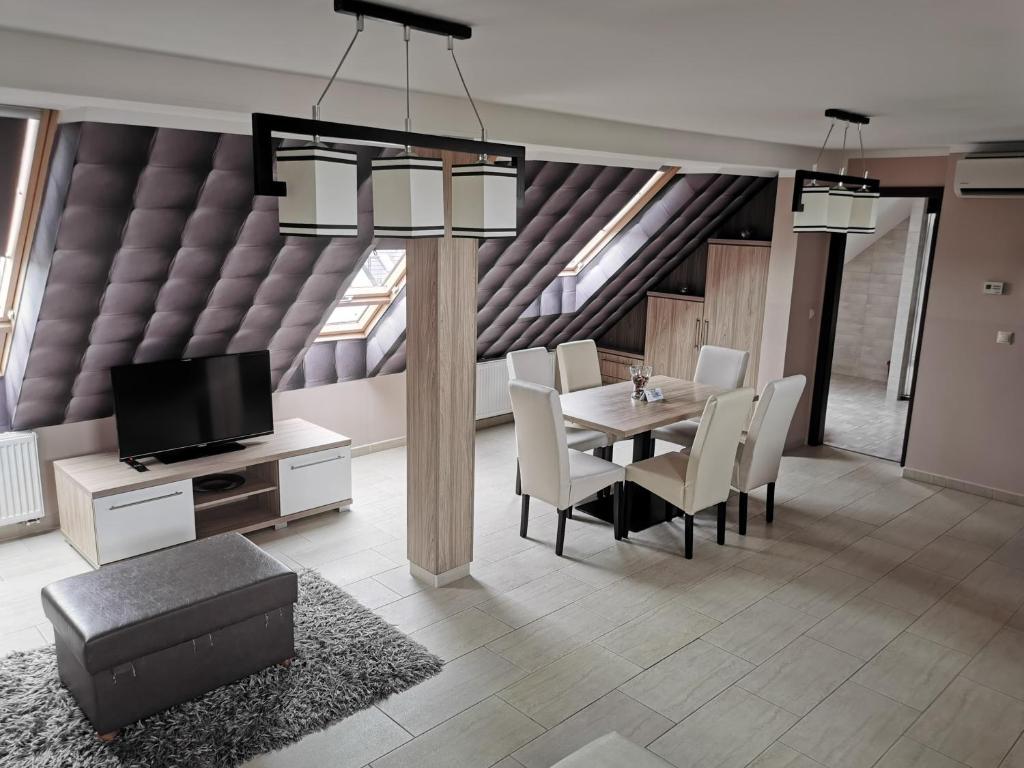 a dining room with a table and chairs and a tv at Szabó Lux Apartman in Sárvár
