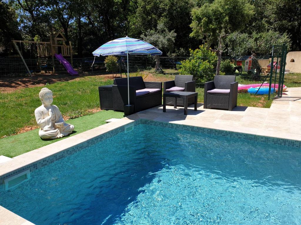 une piscine avec des chaises et un parasol et une statue à côté dans l'établissement Villa parpailloun, jardin, piscine chauffée, à Flayosc