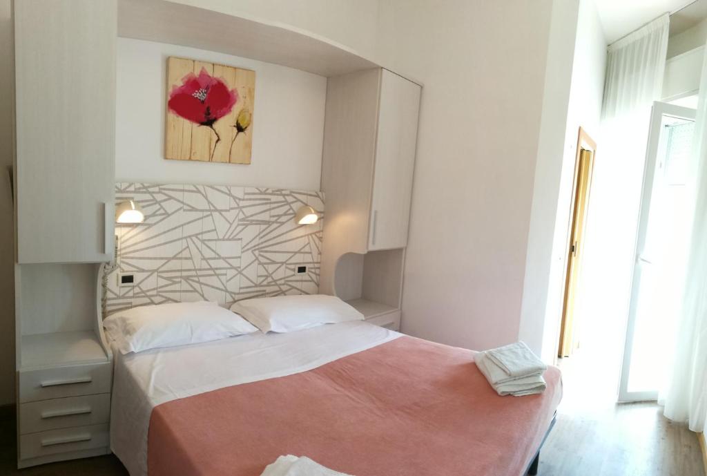 sypialnia z dużym łóżkiem i różowym kocem w obiekcie Hotel Luana w Rimini