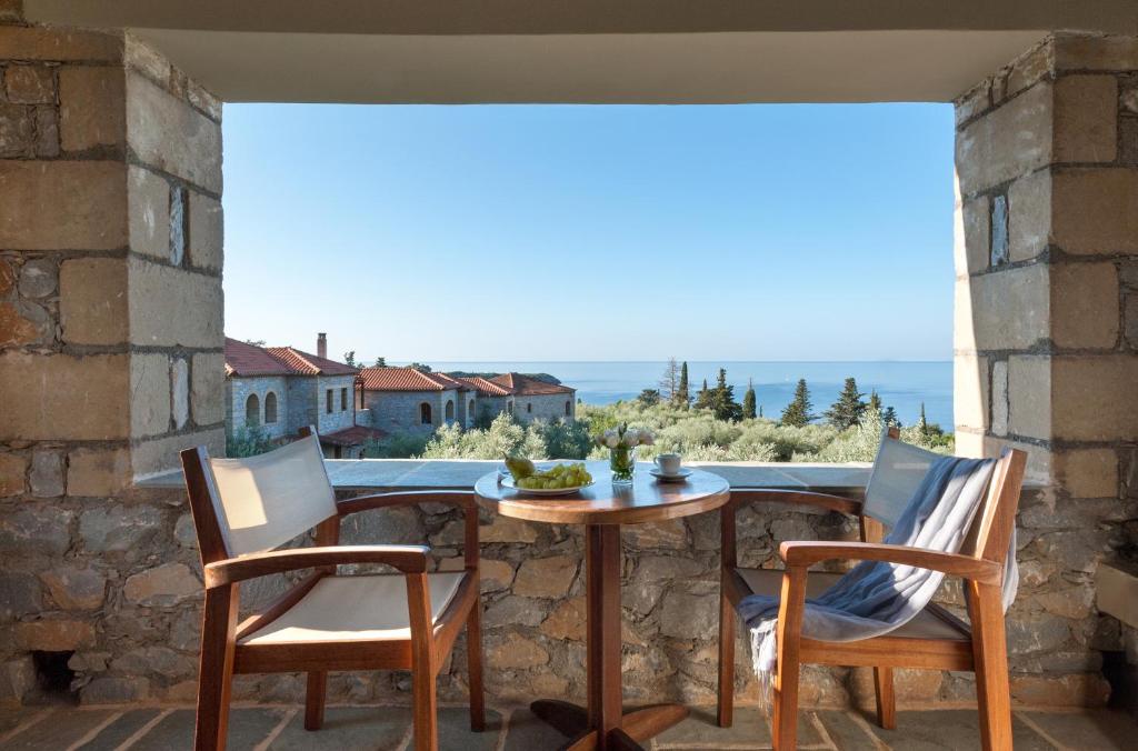 a table and chairs on a balcony with a view at Kalamitsi Hotel in Kardamyli
